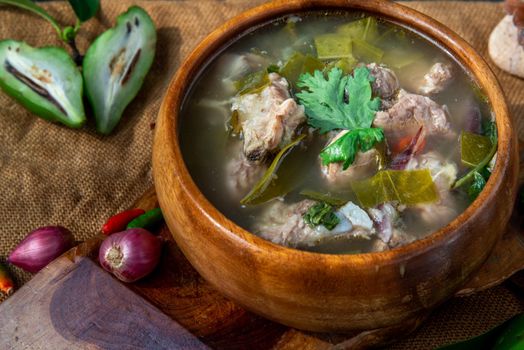 Pork spare rip Madan soup (Kra Dook Moo Tom Ma-Dun) in a wooden bowl, Traditional Thai food, Oblique view from the top.