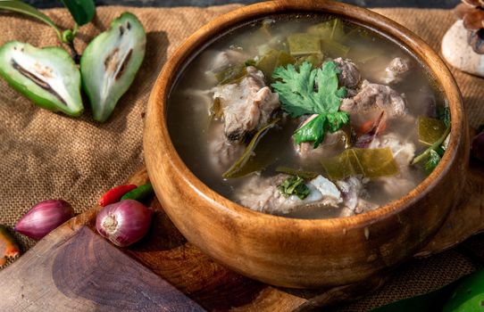 Pork spare rip Madan soup (Kra Dook Moo Tom Ma-Dun) in a wooden bowl, Traditional Thai food, Oblique view from the top.