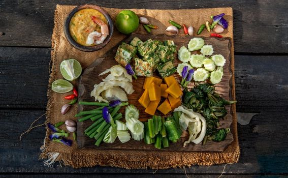 Thai Traditional Local Food : Shrimps chili dip or nam prik with shrimps (Nam Prik Goong Sod) with blanched vegetables and cha-om omelets on wooden backgroud.