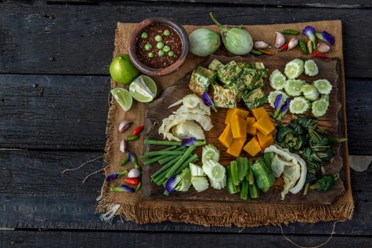 Thai Traditional Local Food : Spicy Shrimp Paste Dip or Fried shrimp paste sauce (Nam Prik Kapi) with blanched vegetables and cha-om omelets on wooden backgroud.