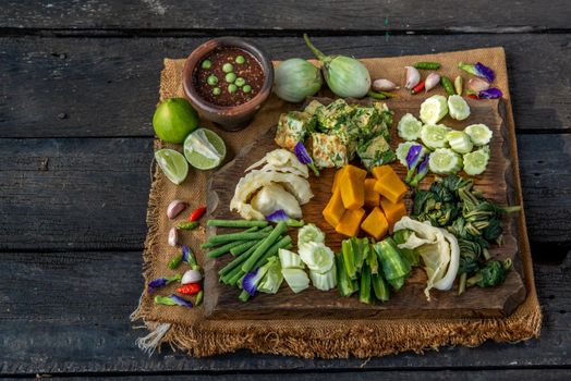Thai Traditional Local Food : Spicy Shrimp Paste Dip or Fried shrimp paste sauce (Nam Prik Kapi) with blanched vegetables and cha-om omelets on wooden backgroud.