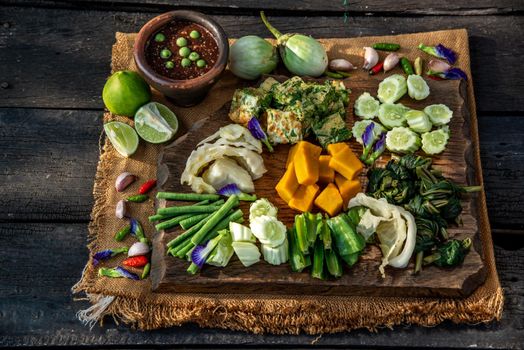 Thai Traditional Local Food : Spicy Shrimp Paste Dip or Fried shrimp paste sauce (Nam Prik Kapi) with blanched vegetables and cha-om omelets on wooden backgroud.