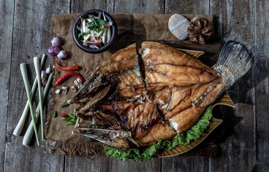Deep fried Snapper with fish sauce on vintage wooden, The perfect frying process, Set hot fire, then bring the snapper to fry to frame and topped with fish sauce.