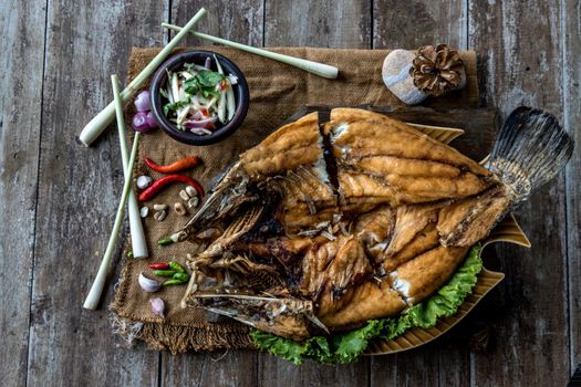 Deep fried Snapper with fish sauce on vintage wooden, The perfect frying process, Set hot fire, then bring the snapper to fry to frame and topped with fish sauce.