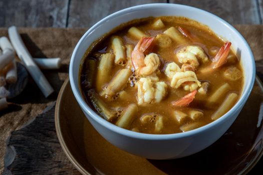 Sour soup with lotus stem and shrimps (kaeng som koong with lotus stem), Traditional Thai food, Oblique view from the top.