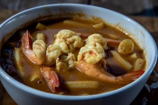Close-up of Sour soup with lotus stem and shrimps (kaeng som koong with lotus stem), Traditional Thai food.