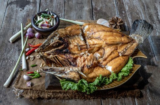 Deep fried Snapper with fish sauce on vintage wooden, The perfect frying process, Set hot fire, then bring the snapper to fry to frame and topped with fish sauce.