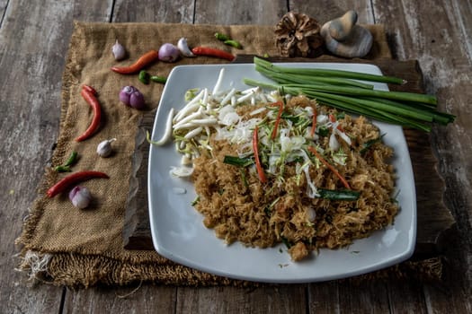 Asian eating food, Mee Grob is an sweet and sour crispy noodles, made from Thai rice noodle with sweet and sour sauce on white plate, Sweet & Sour Crispy Rice Noodles, Oblique view from the top.