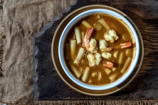 Sour soup with lotus stem and shrimps (kaeng som koong with lotus stem), Traditional Thai food, Top view.