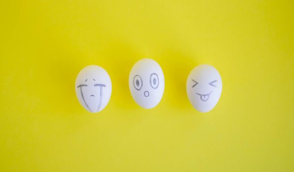 White eggs with funny faces on a yellow background. Easter Concept.