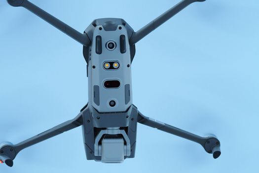 Grey quadcopter, drone with camera flies in the air, view from below. High quality photo