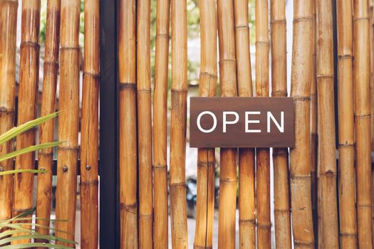 A business sign that says open on cafe or restaurant hang on door at entrance. Vintage color tone style.