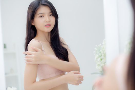 Beautiful sexy young asian woman look mirror applying cream on shoulder and message, beauty girl applying body lotion skin care for health and soft hydration, treatment and cosmetic with moisturizer.