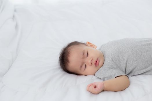 Portrait of asian little baby girl sleeping on bed in the bedroom at home, newborn napping with cozy and relax, infant innocence in bedtime, happy toddler cute, growth of child and emotion, indoors.