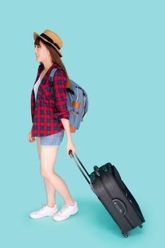 Beautiful young asian woman pulling suitcase isolated on blue background, asia girl having expression is cheerful holding luggage walking in vacation with excited, journey and travel concept.
