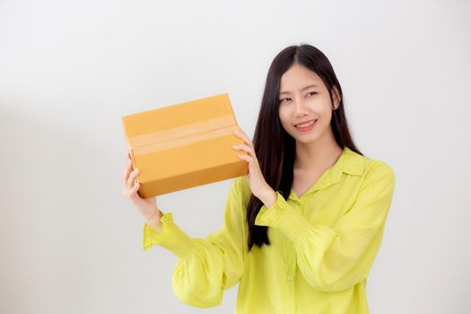 Young asian woman smiling and holding cardboard box with surprise at home, happy female carrying parcel box with excited, present and gift, packaging for deliver, online shopping store and service concept.