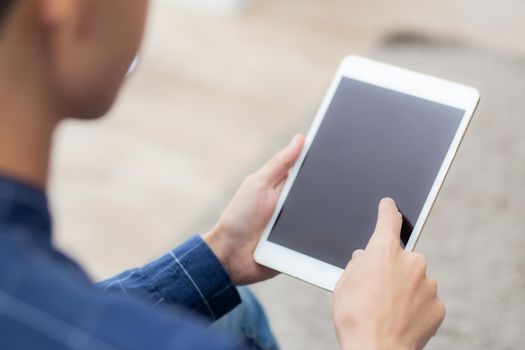 Closeup young asian man sitting and using mockup of tablet computer with display blank screen on sofa at home, male holding digital tablet watch entertainment at living room, communication concept.