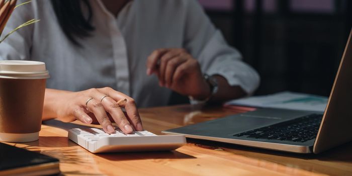 Business accounting concept, Business woman using calculator with computer laptop, budget tax and loan paper in office.