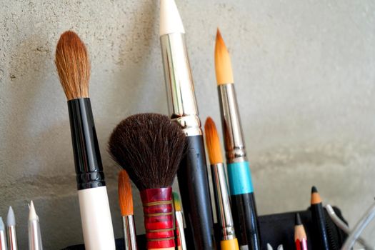 Detail of paint brushes and bright paint in an artist’s studio