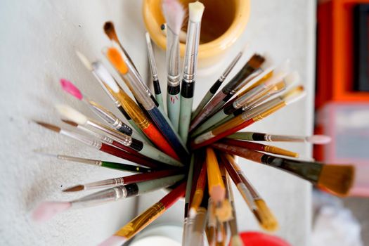 Detail of paint brushes and bright paint in an artist’s studio