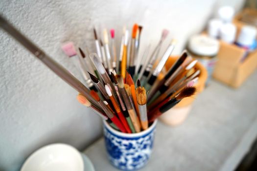 Detail of paint brushes and bright paint in an artist’s studio
