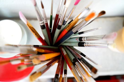 Detail of paint brushes and bright paint in an artist’s studio