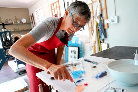 Artist working in her studio wiht paintbrushes and a print