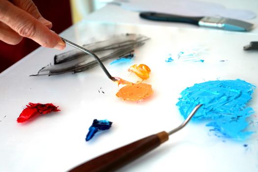 Detail of paint brushes and bright paint in an artist’s studio