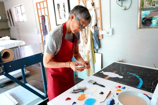 Detail of paint brushes and bright paint in an artist’s studio