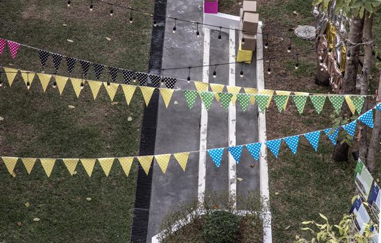 The atmosphere of Preparation lighted decorations and Colorful party flags on a lawn background for Xmas Holiday and New year festival, copy space.