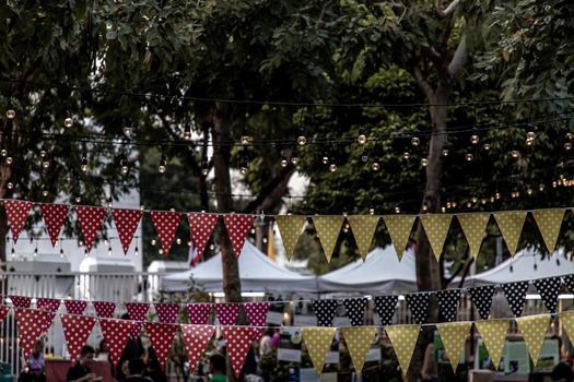Bangkok, Thailand - 22 Dec 2019 : Triangular flags and lighted bulb of decorated for celebrated in garden of evening.