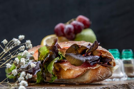 A delicious Smoked salmon sesame bread sandwich on a wooden plate. It is perfect eaten with salads and flavoursome cheeses. Healthy breakfast food.