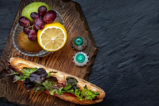 A delicious Smoked salmon sesame bread sandwich with Fresh fruit on a wooden plate. It is perfect eaten with salads and flavoursome cheeses. Healthy breakfast food. Top view. Place for text.