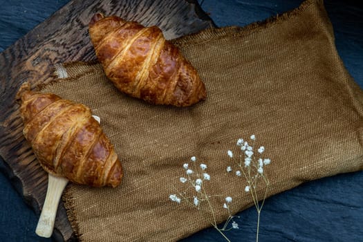 Delicious fresh croissants placed on a wooden plate ready to eat. A delicious French breakfast. Top view, Place for text.