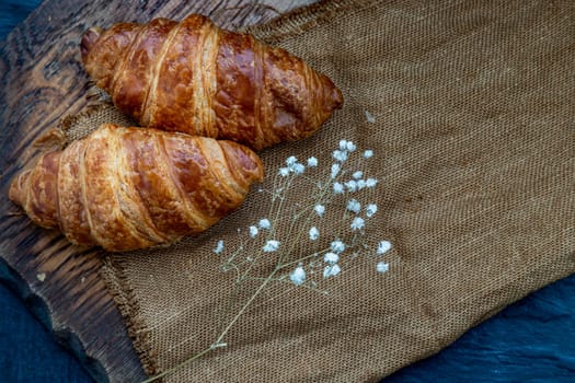 Delicious fresh croissants placed on a wooden plate ready to eat. A delicious French breakfast. Top view, Place for text.