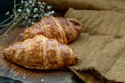 Delicious fresh croissants placed on a wooden plate ready to eat. A delicious French breakfast. Oblique view from the top. Place for text.