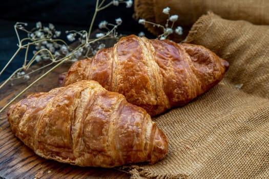 Delicious fresh croissants placed on a wooden plate ready to eat. A delicious French breakfast. Oblique view from the top. Place for text.