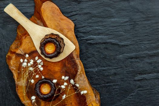 Cannelés (Canelés) de Bordeaux Recipe is a small pastry with rum and vanilla on a wooden plate. Traditional French sweet dessert. tasty snacks. Top view. Place for text.