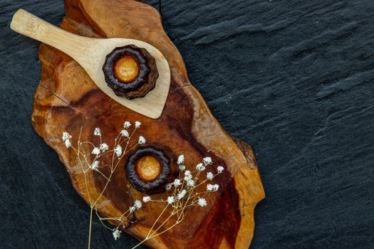 Cannelés (Canelés) de Bordeaux Recipe is a small pastry with rum and vanilla on a wooden plate. Traditional French sweet dessert. tasty snacks. Top view. Place for text.