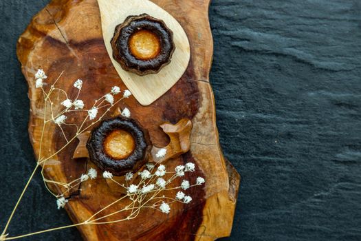 Cannelés (Canelés) de Bordeaux Recipe is a small pastry with rum and vanilla on a wooden plate. Traditional French sweet dessert. tasty snacks. Top view. Place for text.