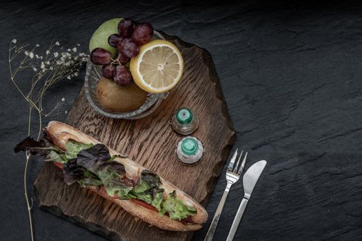 A delicious Smoked salmon sesame bread sandwich with Fresh fruit on a wooden plate. It is perfect eaten with salads and flavoursome cheeses. Healthy breakfast food. Top view. Place for text.