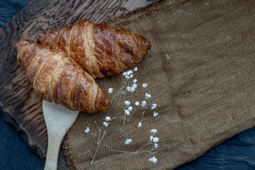 Delicious fresh croissants placed on a wooden plate ready to eat. A delicious French breakfast. Top view, Place for text.