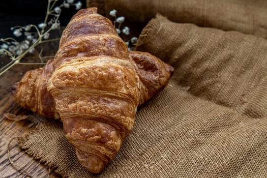 Delicious fresh croissants placed on a wooden plate ready to eat. A delicious French breakfast. Oblique view from the top. Place for text.