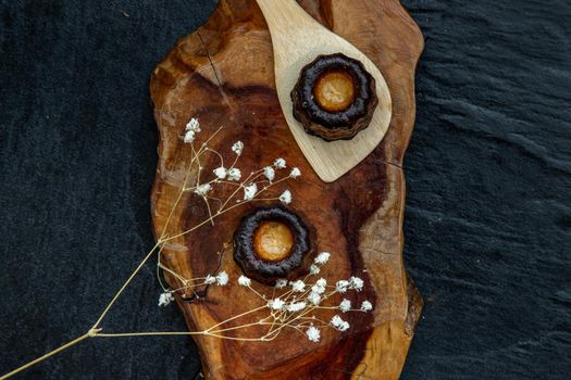 Cannelés (Canelés) de Bordeaux Recipe is a small pastry with rum and vanilla on a wooden plate. Traditional French sweet dessert. tasty snacks. Top view. Place for text.