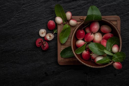 Bengal-Currants, Carandas-plum or Karonda fruit (Carissa carandas L.) sour taste fruit in Wooden cup on wicker. Top view.