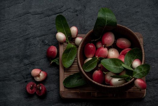Bengal-Currants, Carandas-plum or Karonda fruit (Carissa carandas L.) sour taste fruit in Wooden cup on wicker. Oblique view from the top.