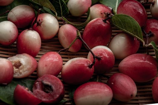 Bengal-Currants, Carandas-plum or Karonda fruit (Carissa carandas L.) sour taste fruit in Wooden cup on wicker. Close-up.