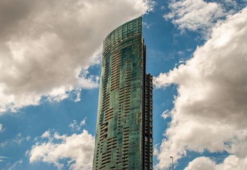 Bangkok, Thailand - 21 Jul 2019 : Angular geometric mirror cladding on a modern building with repeating structure and reflected sky and clouds.