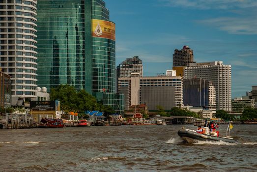 Bangkok, Thailand - 21 Jul 2019 : Police boat rushing on water surface against of Chao Phraya Riverembankment With the backdrop of a beautiful modern building