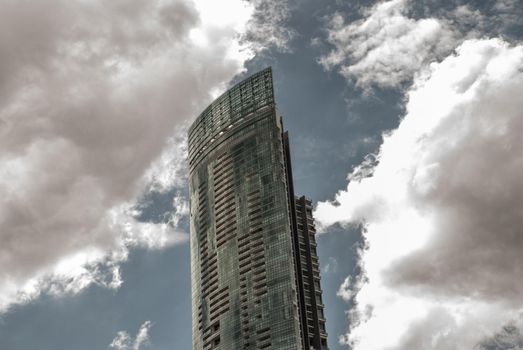 Bangkok, Thailand - 21 Jul 2019 : Angular geometric mirror cladding on a modern building with repeating structure and reflected sky and clouds.